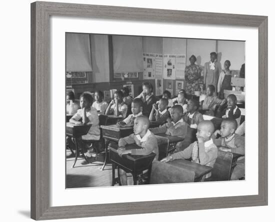 Children Sitting at their Desks in a Classroom, Teachers at the Rear of the Room-null-Framed Photographic Print