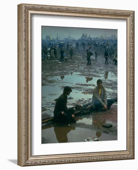 Chuck Morgan Sitting in the Mud and Water with a Friend, During Woodstock Music and Art Fair-John Dominis-Framed Photographic Print