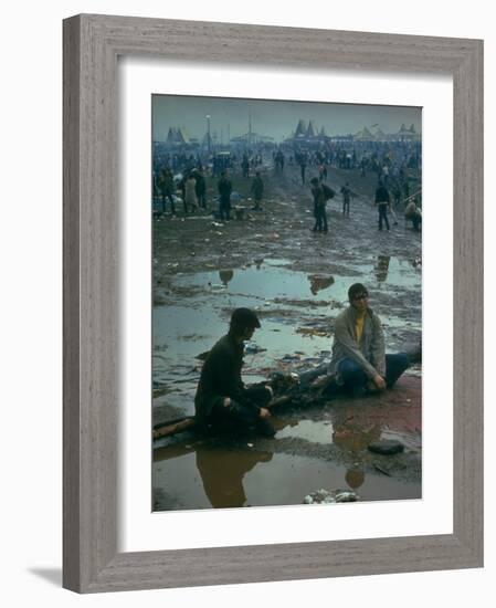 Chuck Morgan Sitting in the Mud and Water with a Friend, During Woodstock Music and Art Fair-John Dominis-Framed Photographic Print