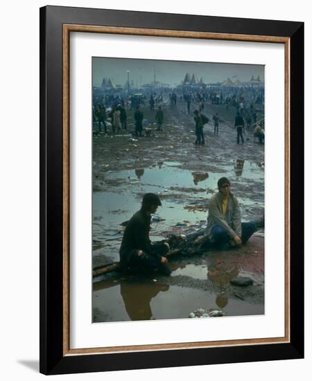 Chuck Morgan Sitting in the Mud and Water with a Friend, During Woodstock Music and Art Fair-John Dominis-Framed Photographic Print