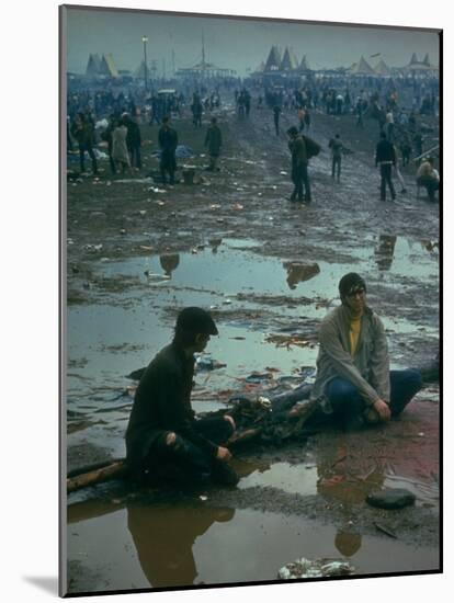 Chuck Morgan Sitting in the Mud and Water with a Friend, During Woodstock Music and Art Fair-John Dominis-Mounted Photographic Print