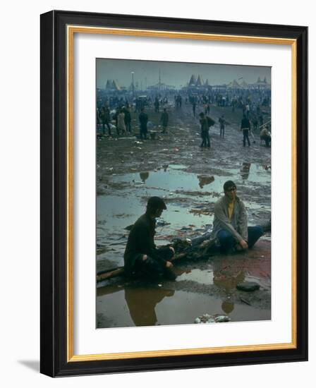 Chuck Morgan Sitting in the Mud and Water with a Friend, During Woodstock Music and Art Fair-John Dominis-Framed Photographic Print