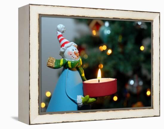 Close-Up of a Snow Man Candle in Front of a Tree with Christmas Lights-Winfred Evers-Framed Premier Image Canvas