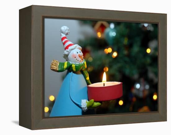 Close-Up of a Snow Man Candle in Front of a Tree with Christmas Lights-Winfred Evers-Framed Premier Image Canvas