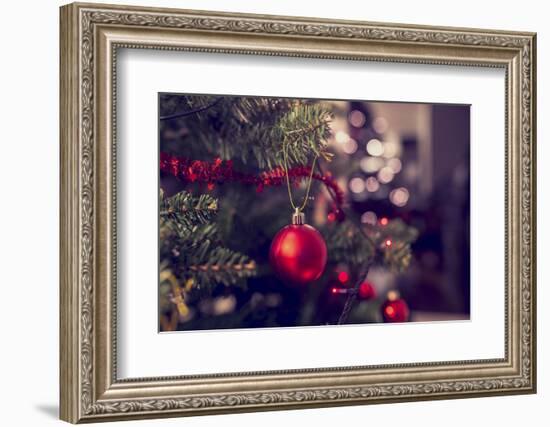 Closeup of Red Bauble Hanging from a Decorated Christmas Tree. Retro Filter Effect.-Gajus-Framed Photographic Print