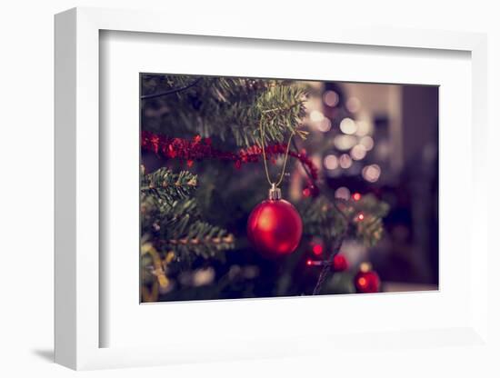 Closeup of Red Bauble Hanging from a Decorated Christmas Tree. Retro Filter Effect.-Gajus-Framed Photographic Print