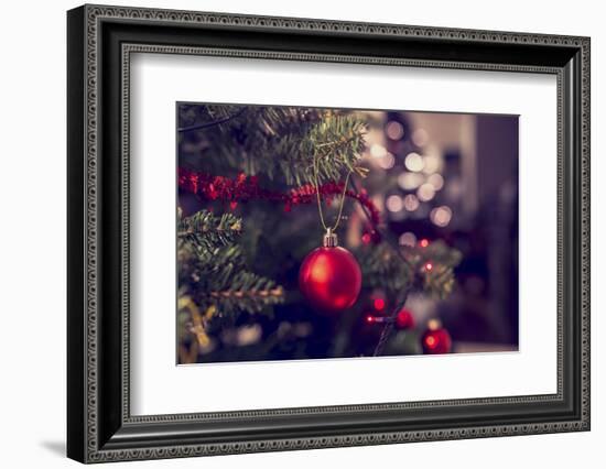 Closeup of Red Bauble Hanging from a Decorated Christmas Tree. Retro Filter Effect.-Gajus-Framed Photographic Print