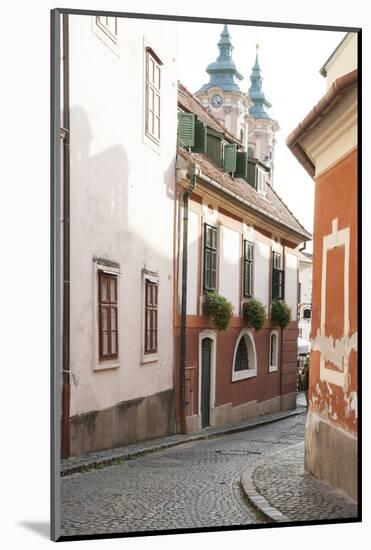 Cobblestone Street and Narrow Buildings with Church Towers in Background, Eger, Hungary-Kimberly Walker-Mounted Photographic Print