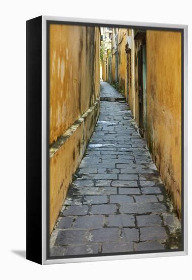 Cobblestones and yellow walls in alleyway, Hoi An, Vietnam-David Wall-Framed Premier Image Canvas