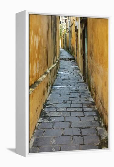 Cobblestones and yellow walls in alleyway, Hoi An, Vietnam-David Wall-Framed Premier Image Canvas