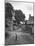 Collie Sheepdog Sitting in Road Leading Up Toward Castle Farm Owned by Beatrix Potter-George Rodger-Mounted Photographic Print