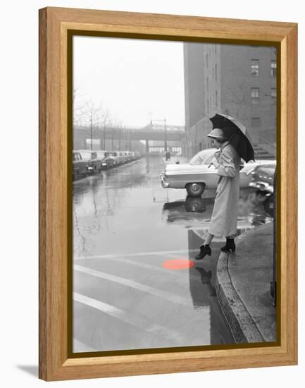 Color Pop,1950s WOMAN IN RAIN COAT HAT BOOTS HOLDING UMBRELLA CROSSING CITY STREET-null-Framed Premier Image Canvas