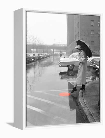 Color Pop,1950s WOMAN IN RAIN COAT HAT BOOTS HOLDING UMBRELLA CROSSING CITY STREET-null-Framed Premier Image Canvas
