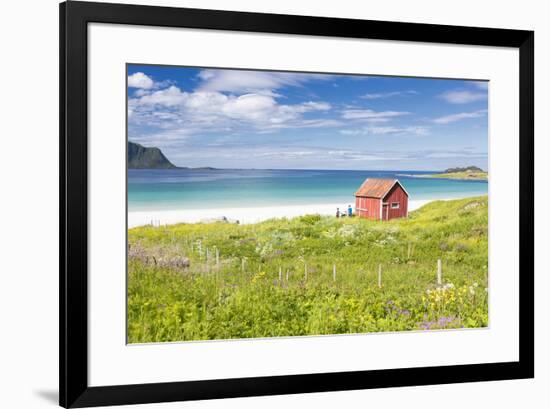 Colorful flowers on green meadows frame the typical rorbu surrounded by turquoise sea, Ramberg, Lof-Roberto Moiola-Framed Photographic Print