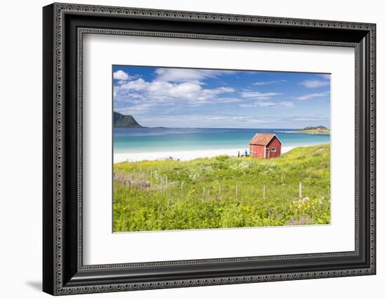 Colorful flowers on green meadows frame the typical rorbu surrounded by turquoise sea, Ramberg, Lof-Roberto Moiola-Framed Photographic Print