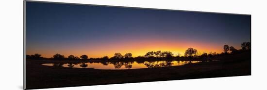 Colorful sunset at watering hole. Camelthorn Lodge. Hwange National Park. Zimbabwe.-Tom Norring-Mounted Photographic Print