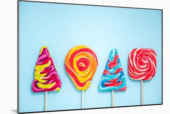 Colorful Vibrant Lollipops, Flat Lay on Blue Background-Marcin Jucha-Mounted Photographic Print