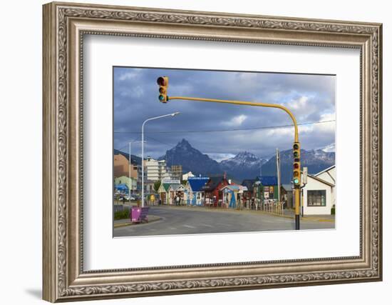 Colourful houses on touristic road framed by traffic lights post with snowy mountain chain beyond, -Fernando Carniel Machado-Framed Photographic Print