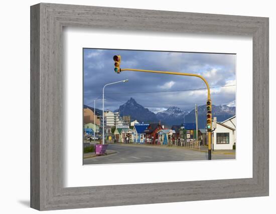 Colourful houses on touristic road framed by traffic lights post with snowy mountain chain beyond, -Fernando Carniel Machado-Framed Photographic Print