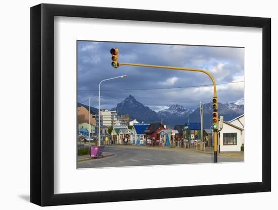 Colourful houses on touristic road framed by traffic lights post with snowy mountain chain beyond, -Fernando Carniel Machado-Framed Photographic Print