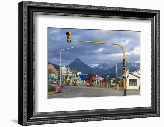 Colourful houses on touristic road framed by traffic lights post with snowy mountain chain beyond, -Fernando Carniel Machado-Framed Photographic Print