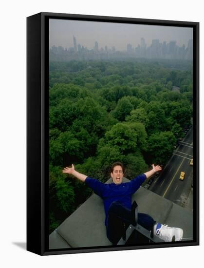 Comedian Jerry Seinfeld Perching Precariously on Roof Ledge Overlooking Central Park-Ted Thai-Framed Premier Image Canvas