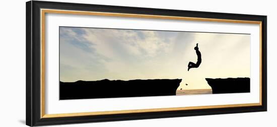 Concept or Conceptual Young Man, Businessman Silhouette Jump Happy from Cliff over Water Gap Sunset-bestdesign36-Framed Photographic Print