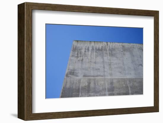 Concrete grey wall with structure and inclusions as a background in front of sky blue cloudless-Axel Killian-Framed Photographic Print