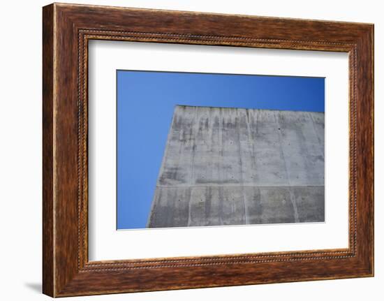 Concrete grey wall with structure and inclusions as a background in front of sky blue cloudless-Axel Killian-Framed Photographic Print