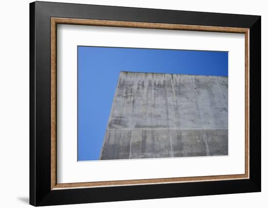 Concrete grey wall with structure and inclusions as a background in front of sky blue cloudless-Axel Killian-Framed Photographic Print