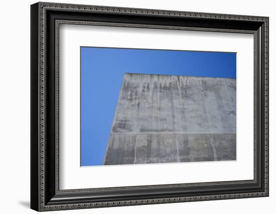 Concrete grey wall with structure and inclusions as a background in front of sky blue cloudless-Axel Killian-Framed Photographic Print