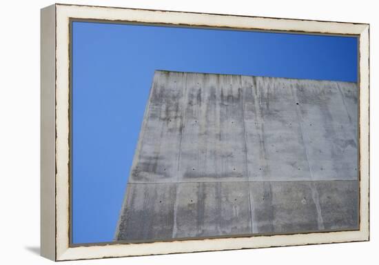 Concrete grey wall with structure and inclusions as a background in front of sky blue cloudless-Axel Killian-Framed Premier Image Canvas