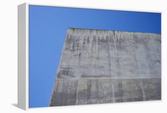 Concrete grey wall with structure and inclusions as a background in front of sky blue cloudless-Axel Killian-Framed Premier Image Canvas