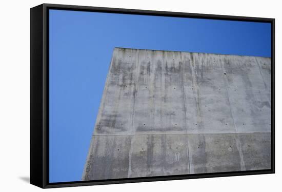 Concrete grey wall with structure and inclusions as a background in front of sky blue cloudless-Axel Killian-Framed Stretched Canvas