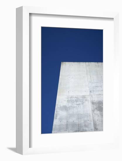 Concrete grey wall with structure and inclusions as a background in front of sky blue cloudless-Axel Killian-Framed Photographic Print