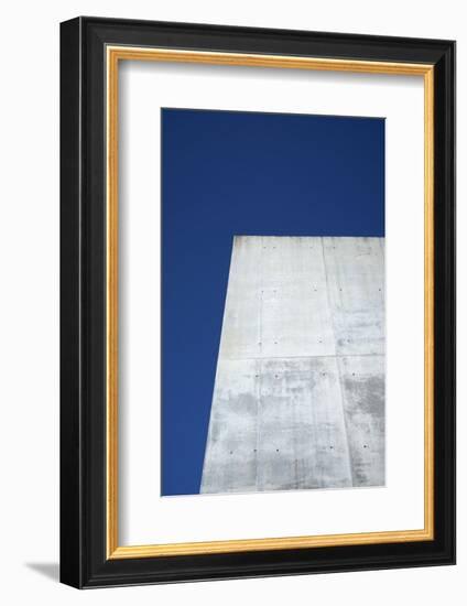 Concrete grey wall with structure and inclusions as a background in front of sky blue cloudless-Axel Killian-Framed Photographic Print