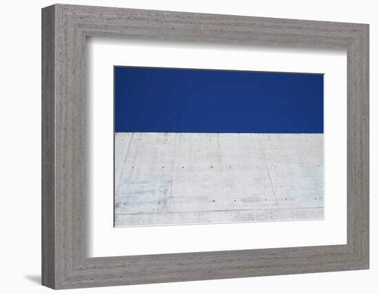 Concrete grey wall with structure and inclusions as a background in front of sky blue cloudless-Axel Killian-Framed Photographic Print