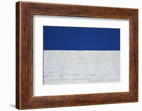 Concrete grey wall with structure and inclusions as a background in front of sky blue cloudless-Axel Killian-Framed Photographic Print