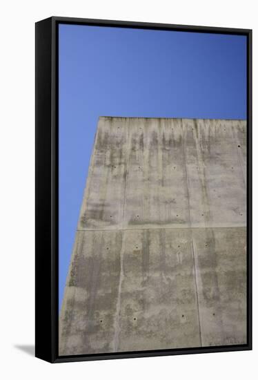 Concrete grey wall with structure and inclusions as a background in front of sky blue cloudless-Axel Killian-Framed Stretched Canvas
