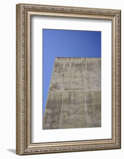 Concrete grey wall with structure and inclusions as a background in front of sky blue cloudless-Axel Killian-Framed Photographic Print