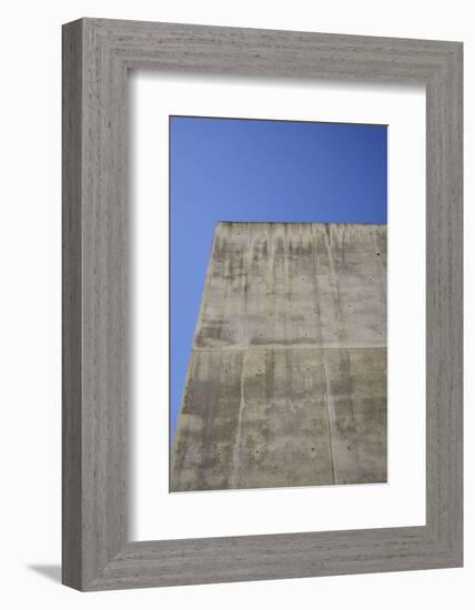 Concrete grey wall with structure and inclusions as a background in front of sky blue cloudless-Axel Killian-Framed Photographic Print