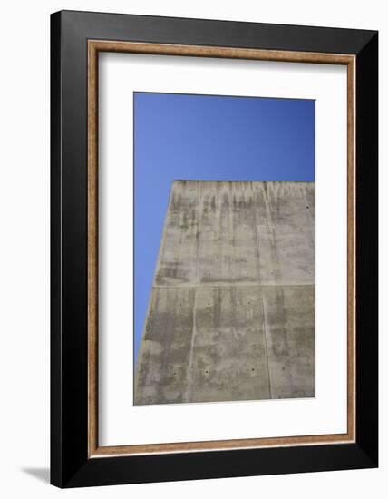 Concrete grey wall with structure and inclusions as a background in front of sky blue cloudless-Axel Killian-Framed Photographic Print