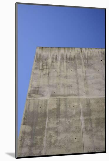 Concrete grey wall with structure and inclusions as a background in front of sky blue cloudless-Axel Killian-Mounted Photographic Print