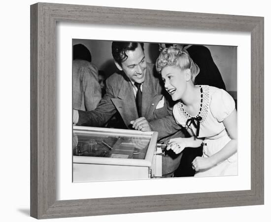 Couple Having Fun and Laughing Next to a Pinball Machine-null-Framed Photo