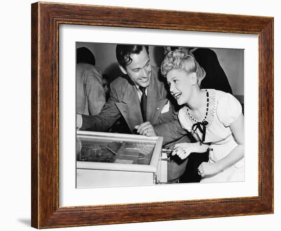 Couple Having Fun and Laughing Next to a Pinball Machine-null-Framed Photo