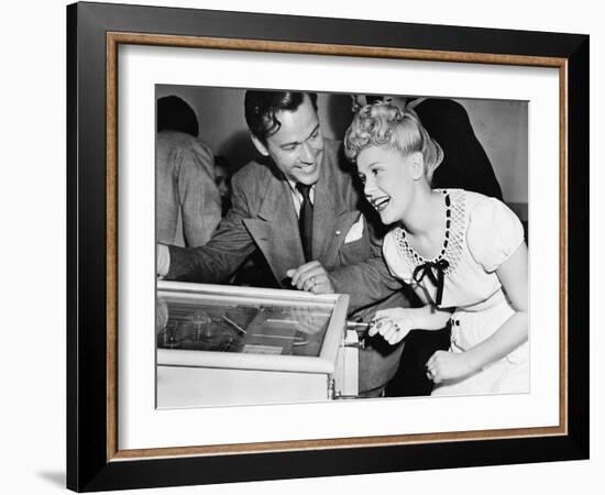 Couple Having Fun and Laughing Next to a Pinball Machine-null-Framed Photo