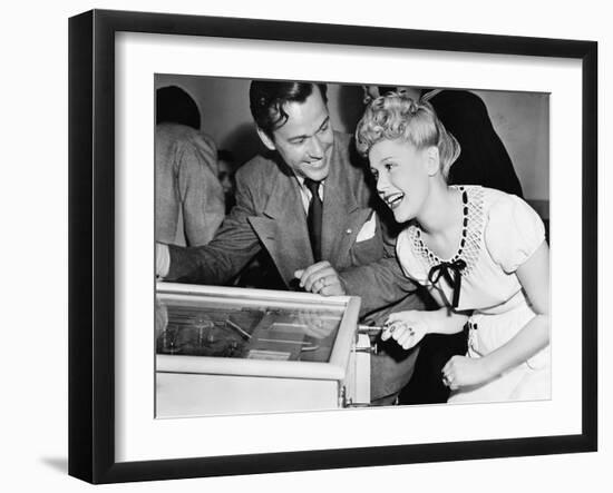 Couple Having Fun and Laughing Next to a Pinball Machine-null-Framed Photo