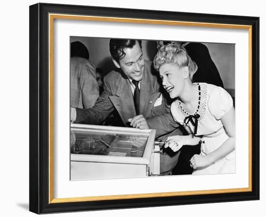 Couple Having Fun and Laughing Next to a Pinball Machine-null-Framed Photo