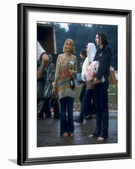 Couple Standing Barefoot on a Road Holding a Bundle and Wine Bottle, Woodstock Music and Art Fair-John Dominis-Framed Photographic Print