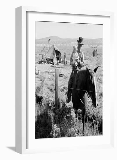 Cowboy Holds His Baby While Riding a Horse-Dorothea Lange-Framed Art Print